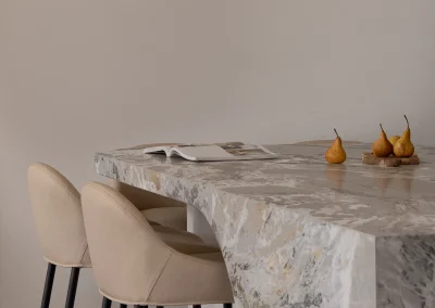 Integrity Stone luxury stone benchtops in a modern Gold Coast kitchen with marble island, chairs, and fruit.
